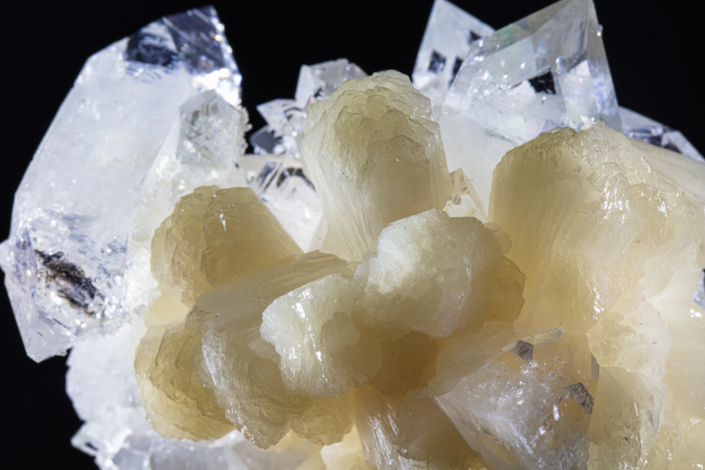 Stilbite crystal cluster macro — close-up showing concentric layered texture and cream color against apophyllite crystals