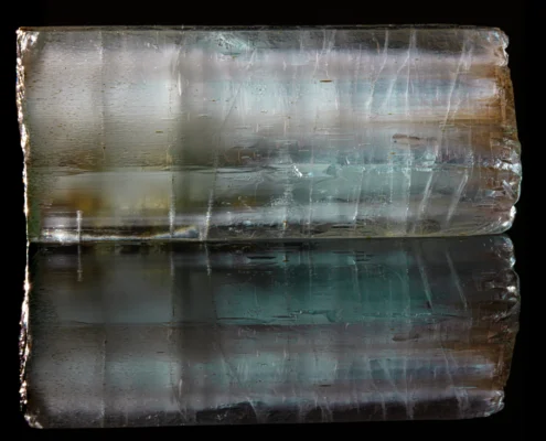 Aquamarine horizontal — Minerals Photography Aquamarine crystal — horizontal macro view on black mirror background showing internal teal color zoning and mirror reflection