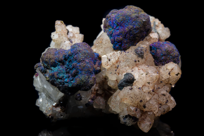 Bornite on quartz — lateral macro view revealing blue teal and gold iridescent surface on bornite nodules against beige quartz matrix