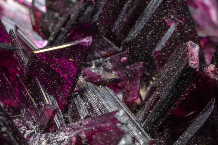 Extreme macro detail of deep purple erythrite crystal faces showing striations, cleavage planes, and translucent layers — macro photography by Minerals Photography