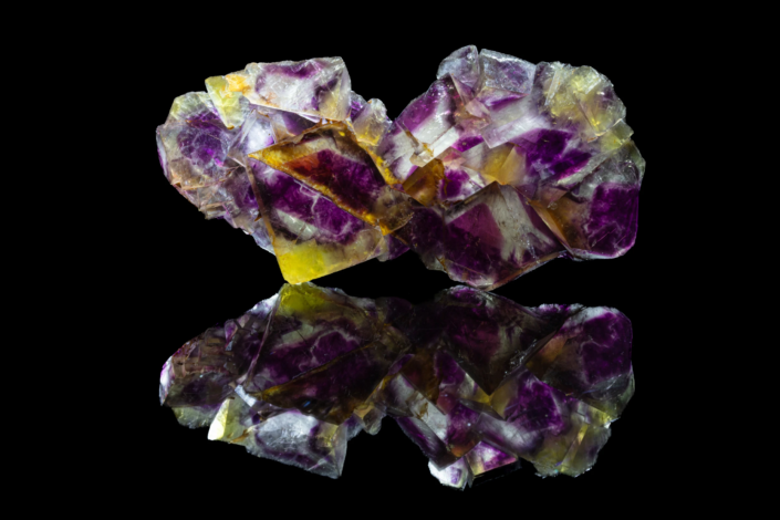Full specimen view of bicolor purple and yellow fluorite cubic crystal cluster with mirror reflection on black background — macro photography by Minerals Photography