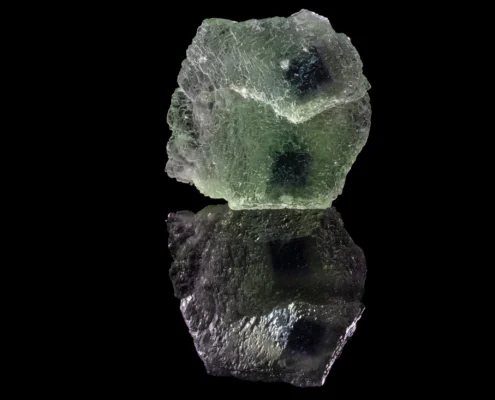 Green Etched Fluorite with Dark Phantom Inclusions — Minerals Photography Full specimen view of pale green etched fluorite cubic crystal with dark phantom inclusions visible through translucent body, mirror reflection on black background — macro photography by Minerals Photography