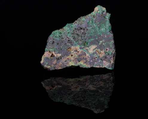 Jaguéite — Full Specimen with Reflection — Minerals Photography Jaguéite specimen with metallic gray-purple surface and bright green secondary mineral coatings on black reflective surface, macro photography by Minerals Photography