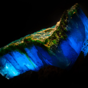 Krohnkite and natrochalcite specimen illuminated from behind, revealing deep electric blue translucency and green mineral veining, macro photography by Minerals Photography
