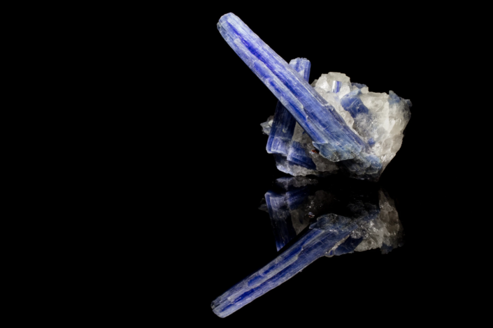 Blue kyanite bladed crystals on white quartz matrix reflected on black surface, macro photography by Minerals Photography